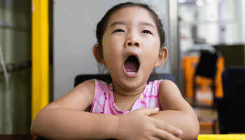 Child sat at a table and yawning image