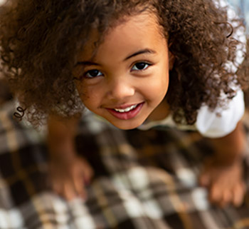 Cute little girl playing on blanket and looking up - stock photo